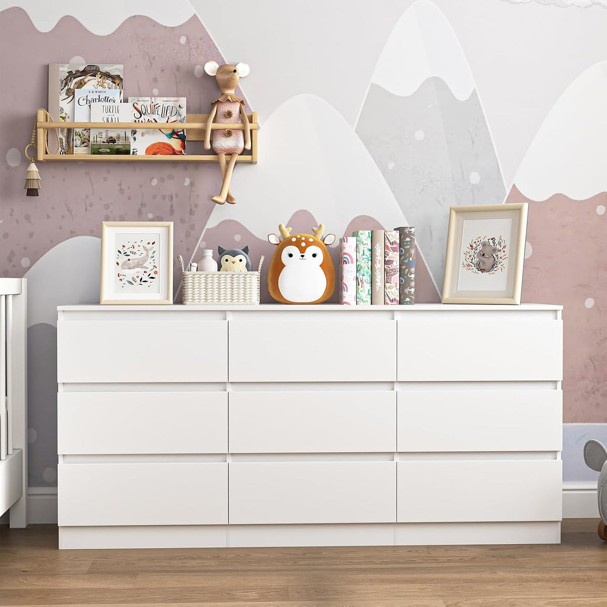 White nine-drawer dresser styled with books and toys in a pink room